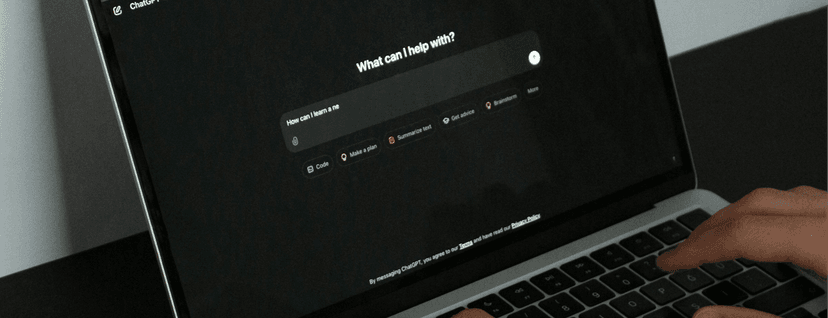 Jemand sitzt vor einem Laptop, auf dem ein KI-Chatbot im dunklen Modus läuft. Der Nutzer tippt auf der Tastatur.